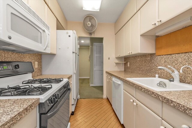 kitchen with light wood-type flooring, white appliances, tasteful backsplash, and sink