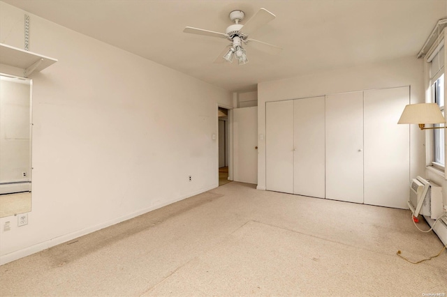 unfurnished bedroom with a closet, a wall unit AC, ceiling fan, and a baseboard radiator