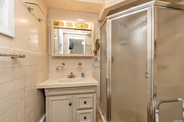 bathroom with vanity, an enclosed shower, and tile walls