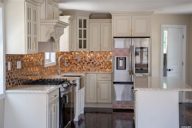 kitchen with decorative backsplash, dark hardwood / wood-style floors, light stone countertops, a kitchen island, and stainless steel appliances