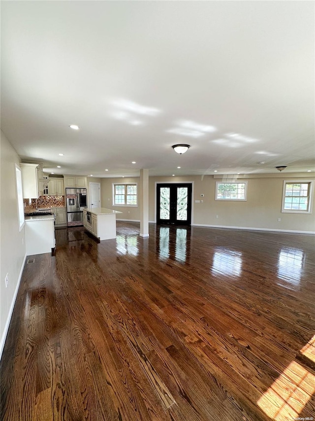 unfurnished living room with dark hardwood / wood-style floors and french doors