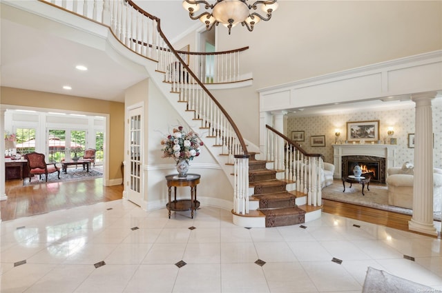 stairs featuring ornate columns, hardwood / wood-style floors, a towering ceiling, and a notable chandelier