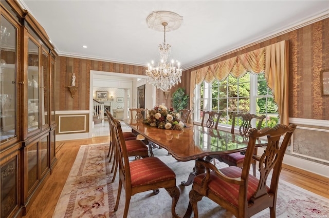 dining room featuring an inviting chandelier, light hardwood / wood-style flooring, and crown molding