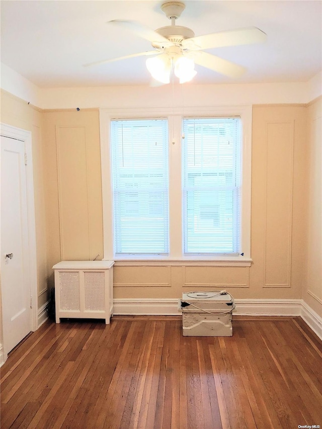 spare room featuring ceiling fan, radiator heating unit, and dark hardwood / wood-style floors