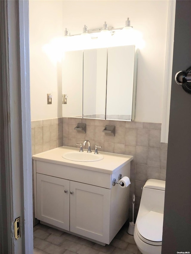 bathroom featuring tile patterned floors, vanity, toilet, and tile walls