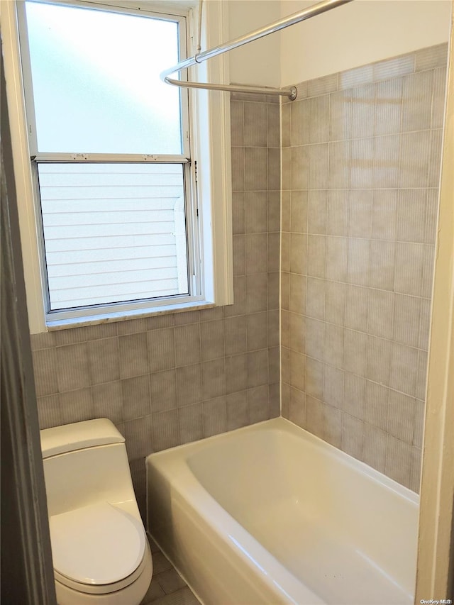 bathroom featuring tile walls, tile patterned flooring, tiled shower / bath combo, and toilet