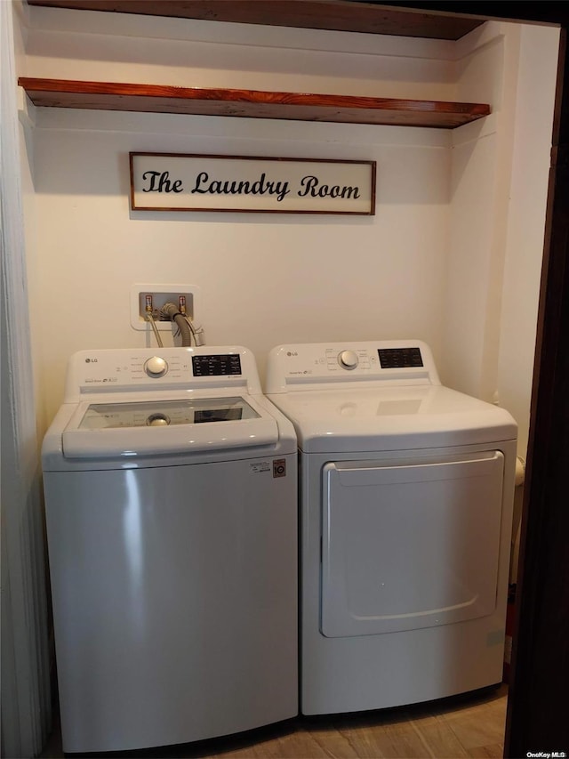 laundry room with light wood-type flooring and washer and clothes dryer