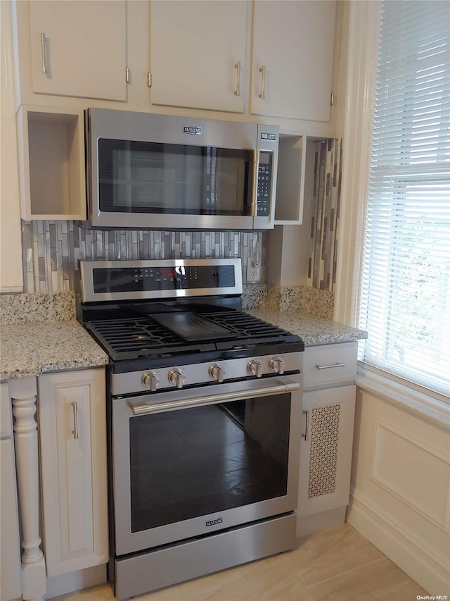 kitchen featuring white cabinetry, decorative backsplash, light stone countertops, and stainless steel appliances