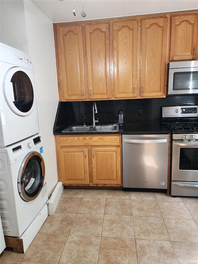 kitchen featuring sink, stainless steel appliances, tasteful backsplash, stacked washer and dryer, and light tile patterned flooring