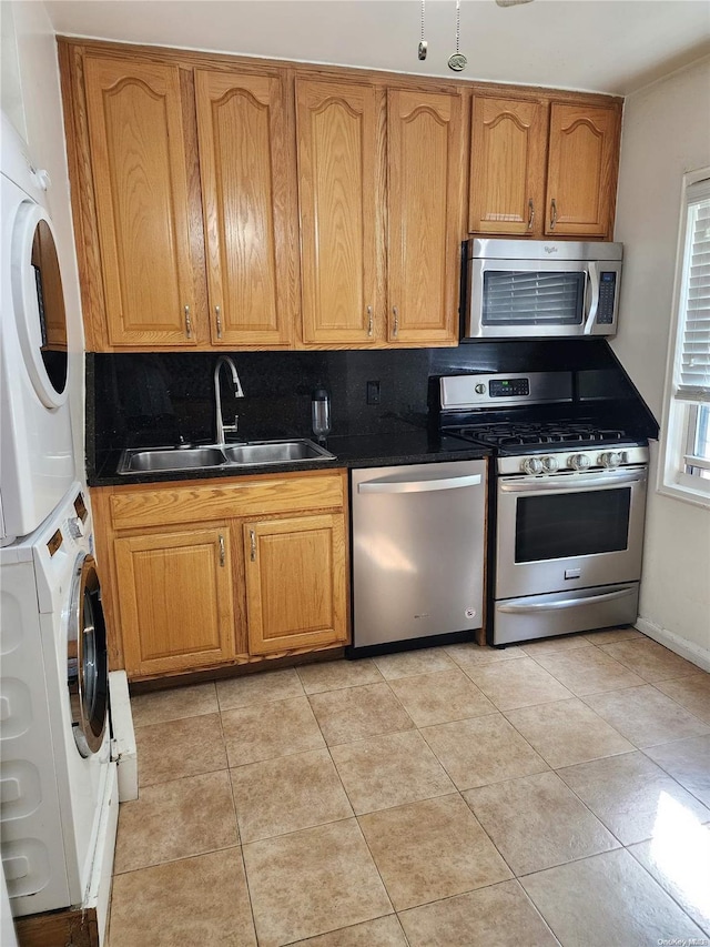 kitchen featuring appliances with stainless steel finishes, backsplash, stacked washer and clothes dryer, and sink