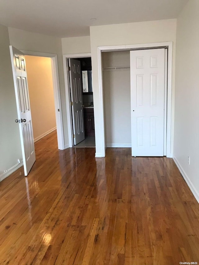 unfurnished bedroom with a closet, dark hardwood / wood-style flooring, and ensuite bathroom