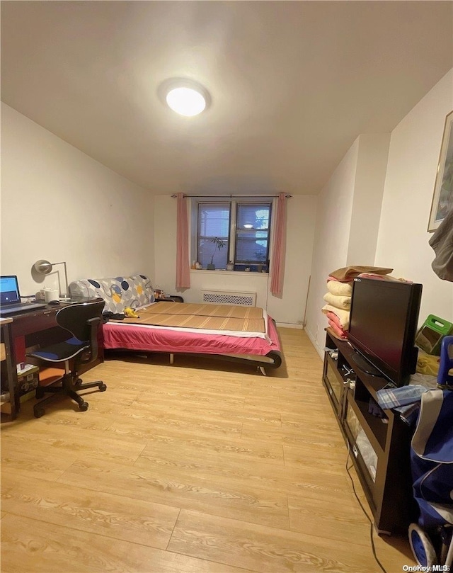 bedroom featuring radiator heating unit and light wood-type flooring