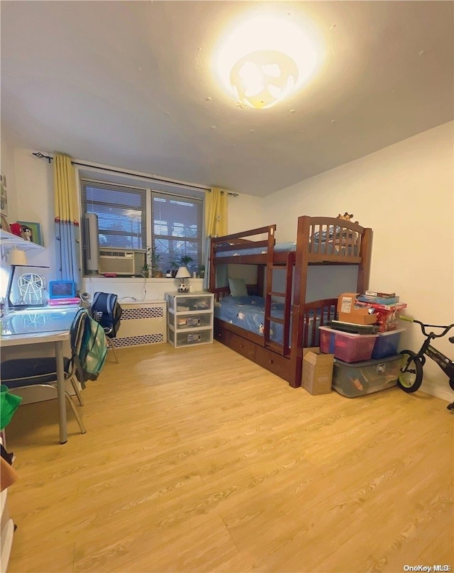 bedroom featuring hardwood / wood-style flooring, radiator, and cooling unit