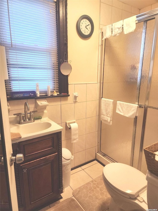 bathroom with tile patterned floors, an enclosed shower, vanity, tile walls, and toilet