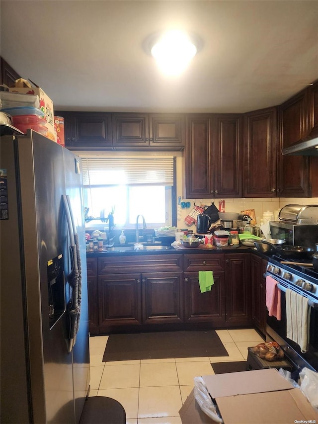 kitchen featuring sink, stainless steel refrigerator with ice dispenser, gas range, dark brown cabinets, and light tile patterned flooring