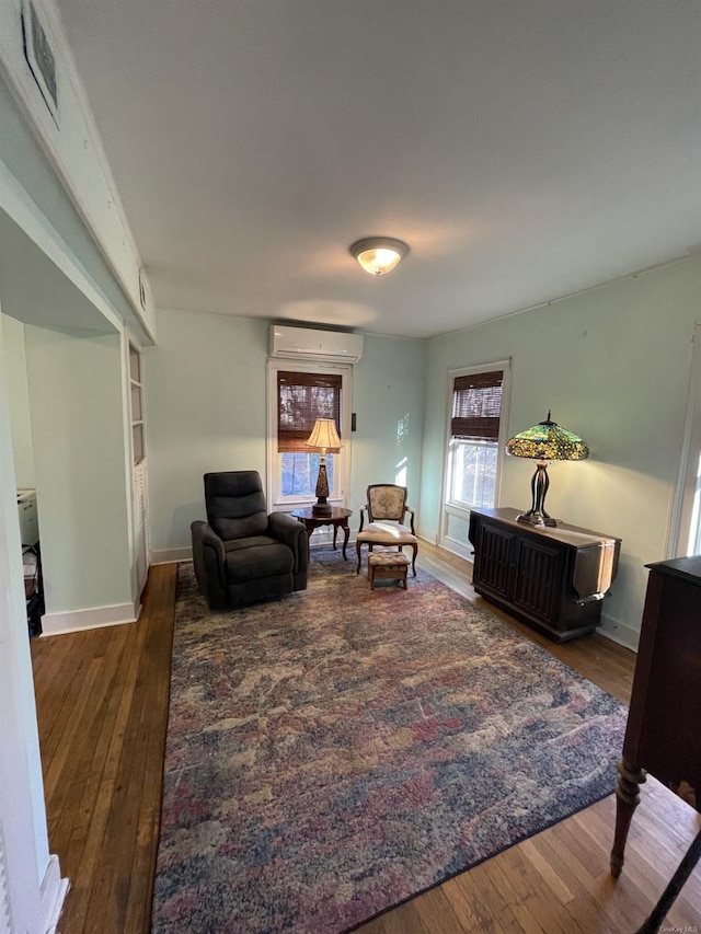 living area featuring a wall unit AC and dark wood-type flooring