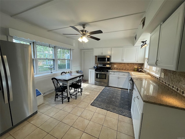 kitchen featuring tasteful backsplash, light tile patterned floors, white cabinetry, appliances with stainless steel finishes, and a sink