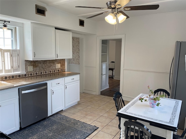 kitchen featuring white cabinetry, appliances with stainless steel finishes, ceiling fan, and wainscoting