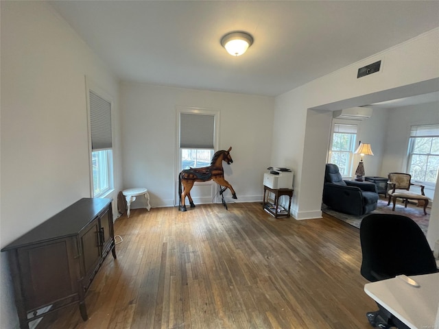 office area with a wall mounted AC, baseboards, dark wood-style floors, and visible vents