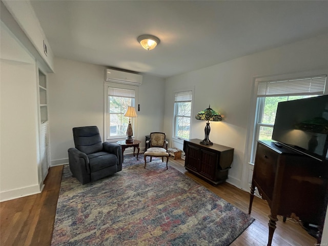 living area featuring a wall mounted AC, wood finished floors, baseboards, and visible vents