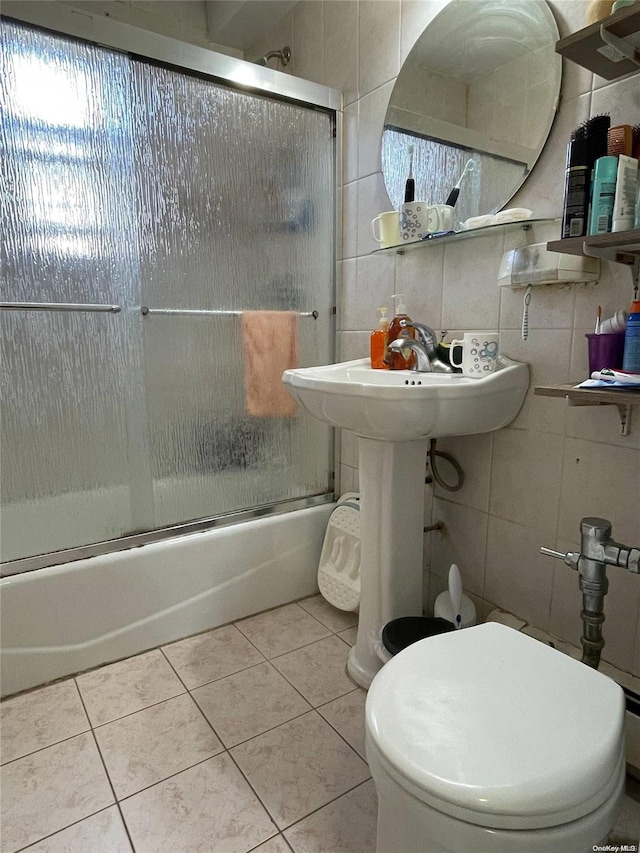 bathroom with tile patterned floors, toilet, enclosed tub / shower combo, and tile walls