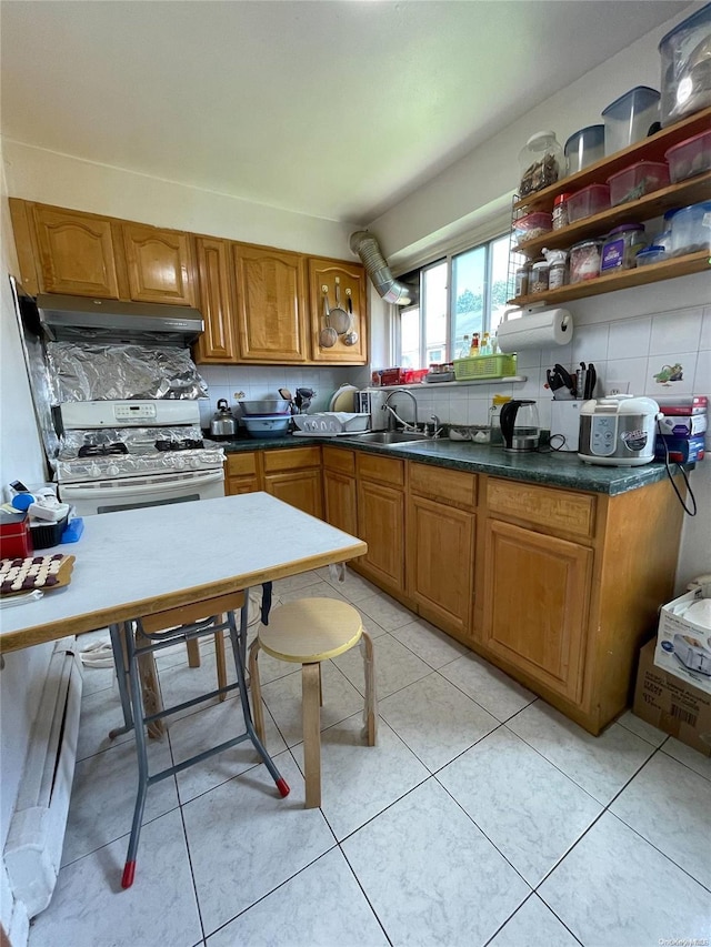 kitchen with sink, decorative backsplash, light tile patterned floors, white gas range, and range hood