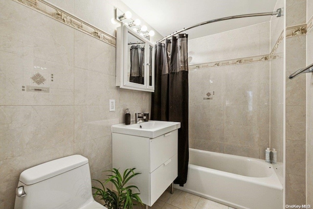 full bathroom featuring tile patterned floors, vanity, shower / bath combo with shower curtain, tile walls, and toilet