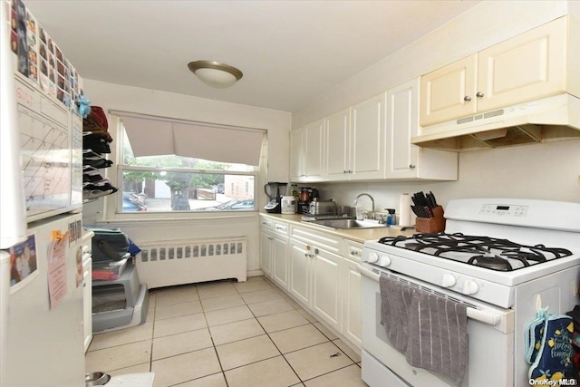 kitchen featuring gas range gas stove, radiator heating unit, sink, light tile patterned flooring, and white cabinets