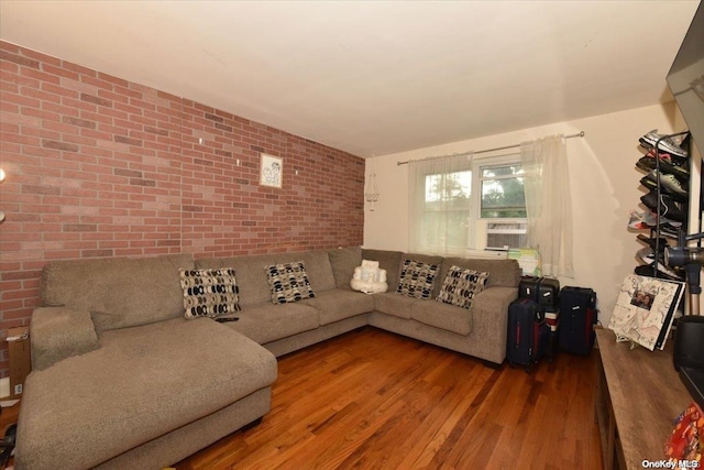 living room with hardwood / wood-style floors, cooling unit, and brick wall