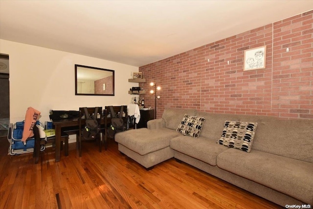 living room with wood-type flooring and brick wall