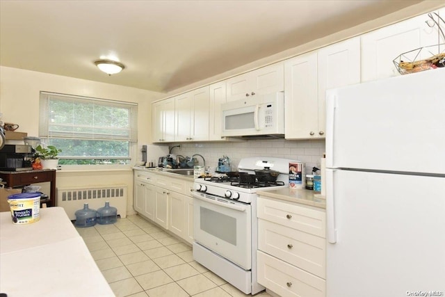 kitchen with white appliances, backsplash, radiator, white cabinets, and light tile patterned floors