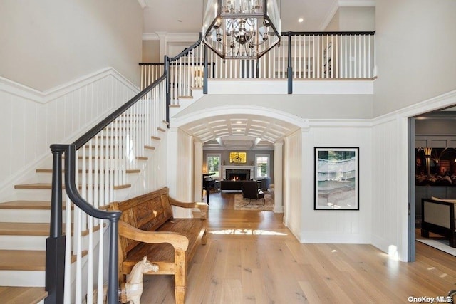 foyer with light wood-type flooring, crown molding, and a high ceiling