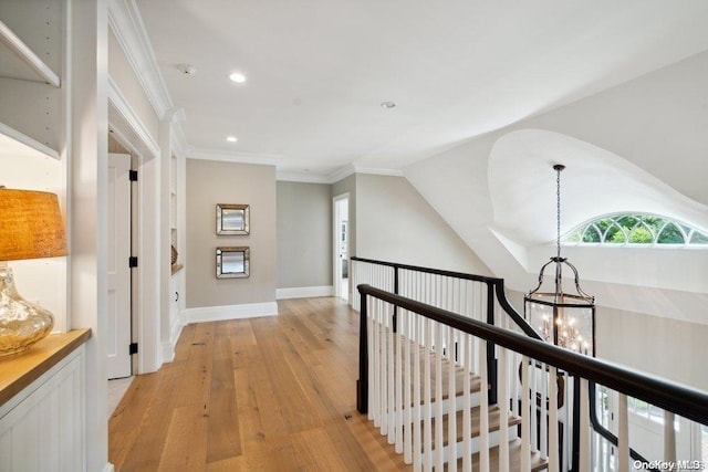 hallway with light hardwood / wood-style floors, crown molding, and a notable chandelier