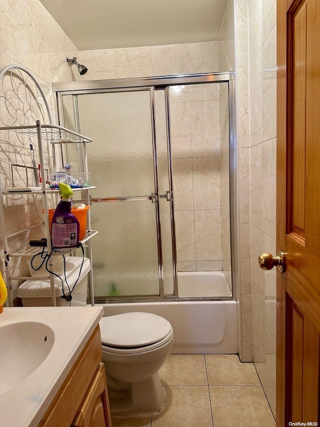 full bathroom featuring combined bath / shower with glass door, vanity, tile patterned floors, and toilet