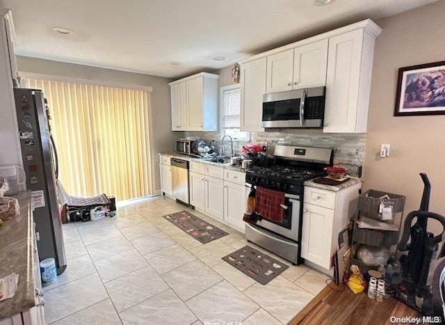 kitchen with backsplash, white cabinetry, sink, and appliances with stainless steel finishes