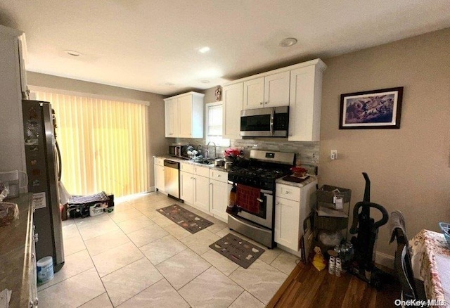 kitchen featuring sink, white cabinets, light tile patterned floors, and appliances with stainless steel finishes