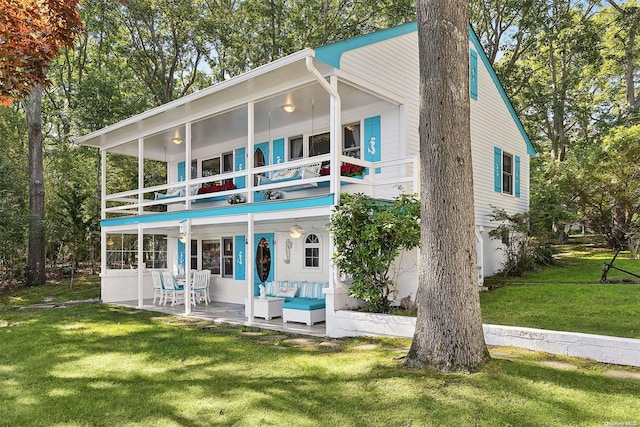 back of property with a lawn, outdoor lounge area, a balcony, and a patio