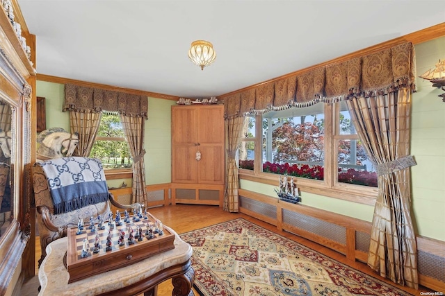 living area with hardwood / wood-style flooring and ornamental molding