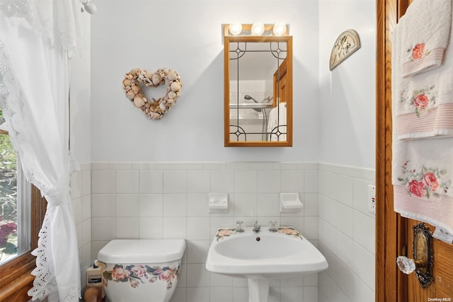 bathroom with toilet, tile walls, and sink