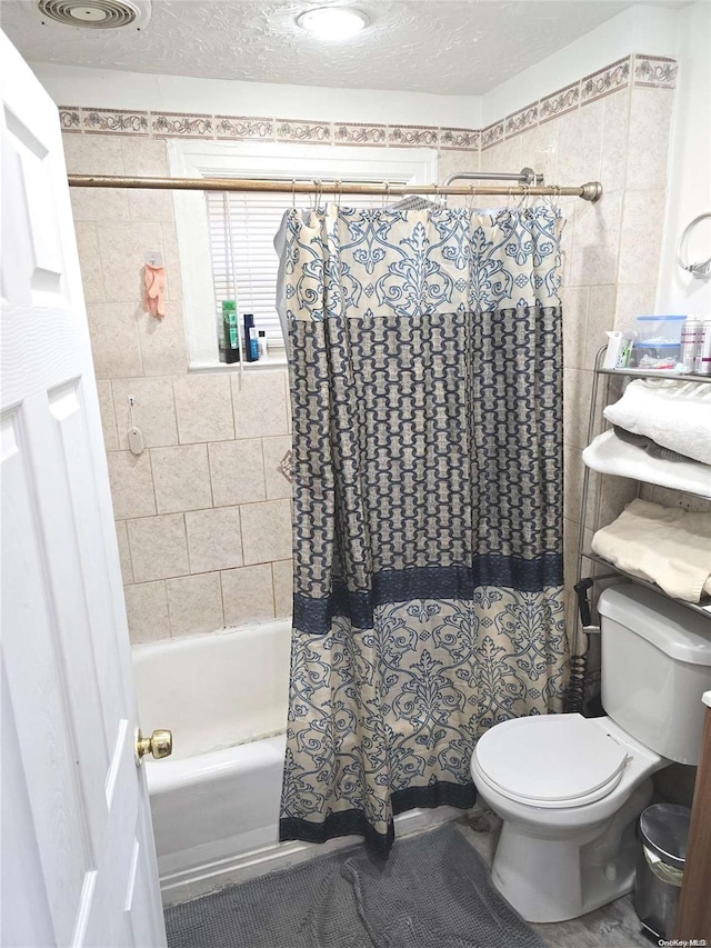 bathroom with toilet, shower / bathtub combination with curtain, and a textured ceiling