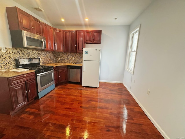 kitchen featuring light stone countertops, appliances with stainless steel finishes, decorative backsplash, sink, and dark hardwood / wood-style floors