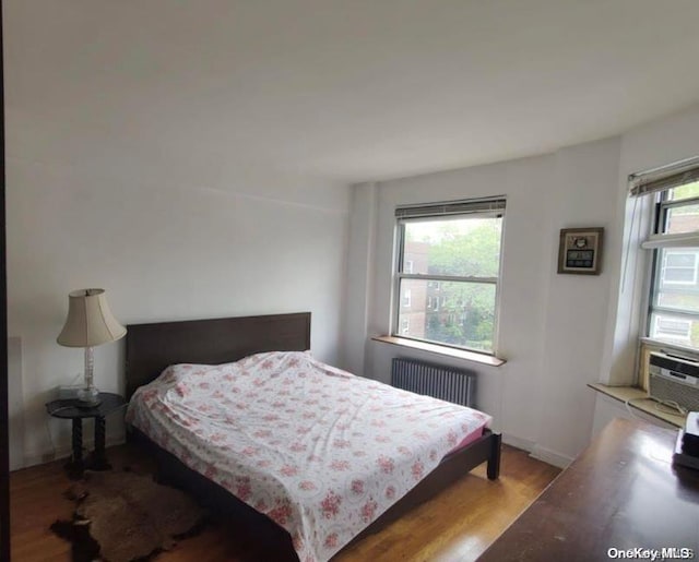 bedroom featuring radiator and hardwood / wood-style floors