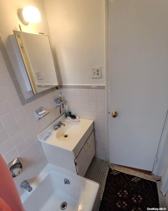 bathroom with tile patterned flooring, a bath, vanity, and tile walls