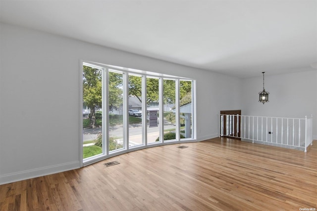 unfurnished living room with a chandelier, a healthy amount of sunlight, and light hardwood / wood-style floors