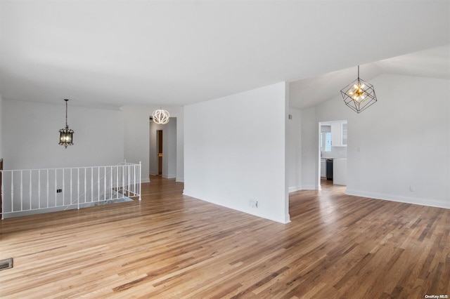 unfurnished living room featuring a chandelier, lofted ceiling, and light hardwood / wood-style flooring