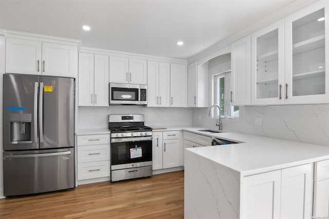 kitchen featuring sink, light stone countertops, appliances with stainless steel finishes, light hardwood / wood-style floors, and white cabinetry