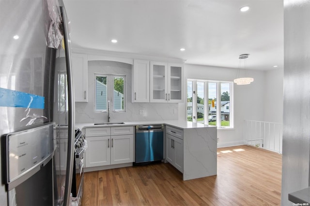 kitchen with a wealth of natural light, white cabinetry, sink, and appliances with stainless steel finishes