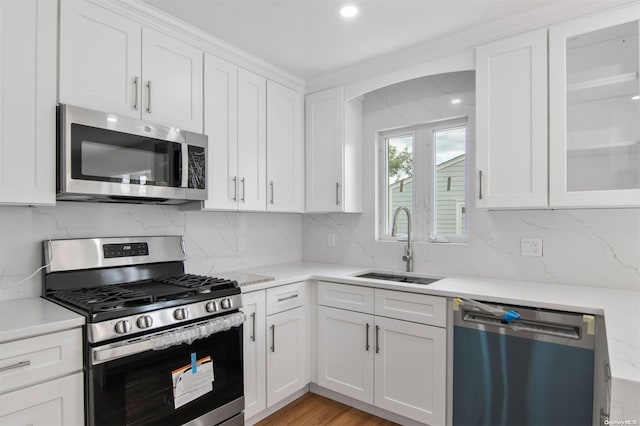 kitchen with backsplash, sink, white cabinets, and stainless steel appliances