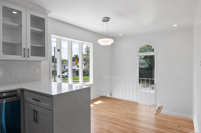 kitchen with light stone countertops, light hardwood / wood-style floors, a wealth of natural light, and gray cabinetry