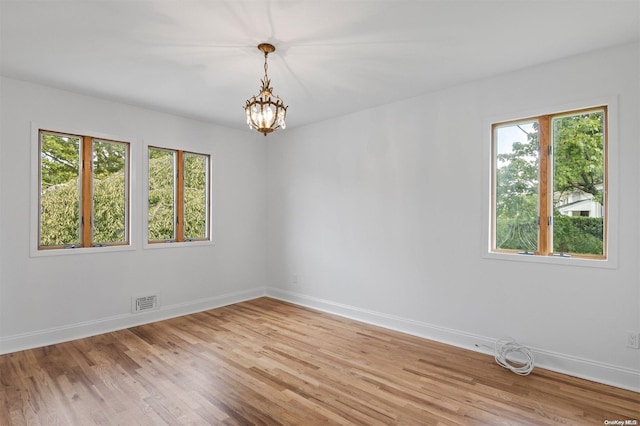 unfurnished room featuring light wood-type flooring and an inviting chandelier